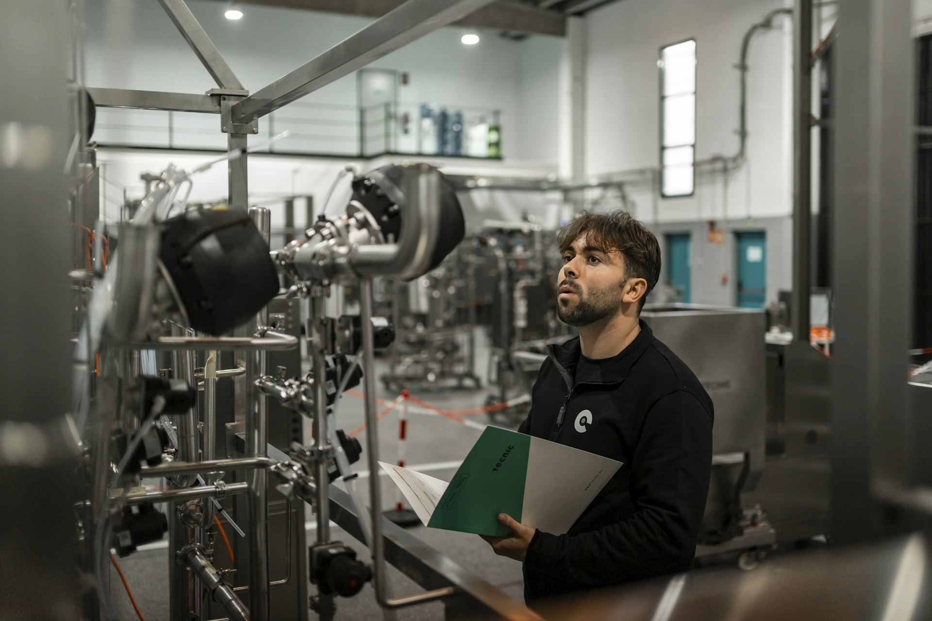 Técnico revisando la maquinaria de una planta industrial con el informe en la mano