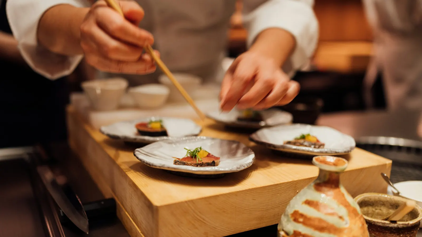Manos emplatando varios platos de cocina creativa