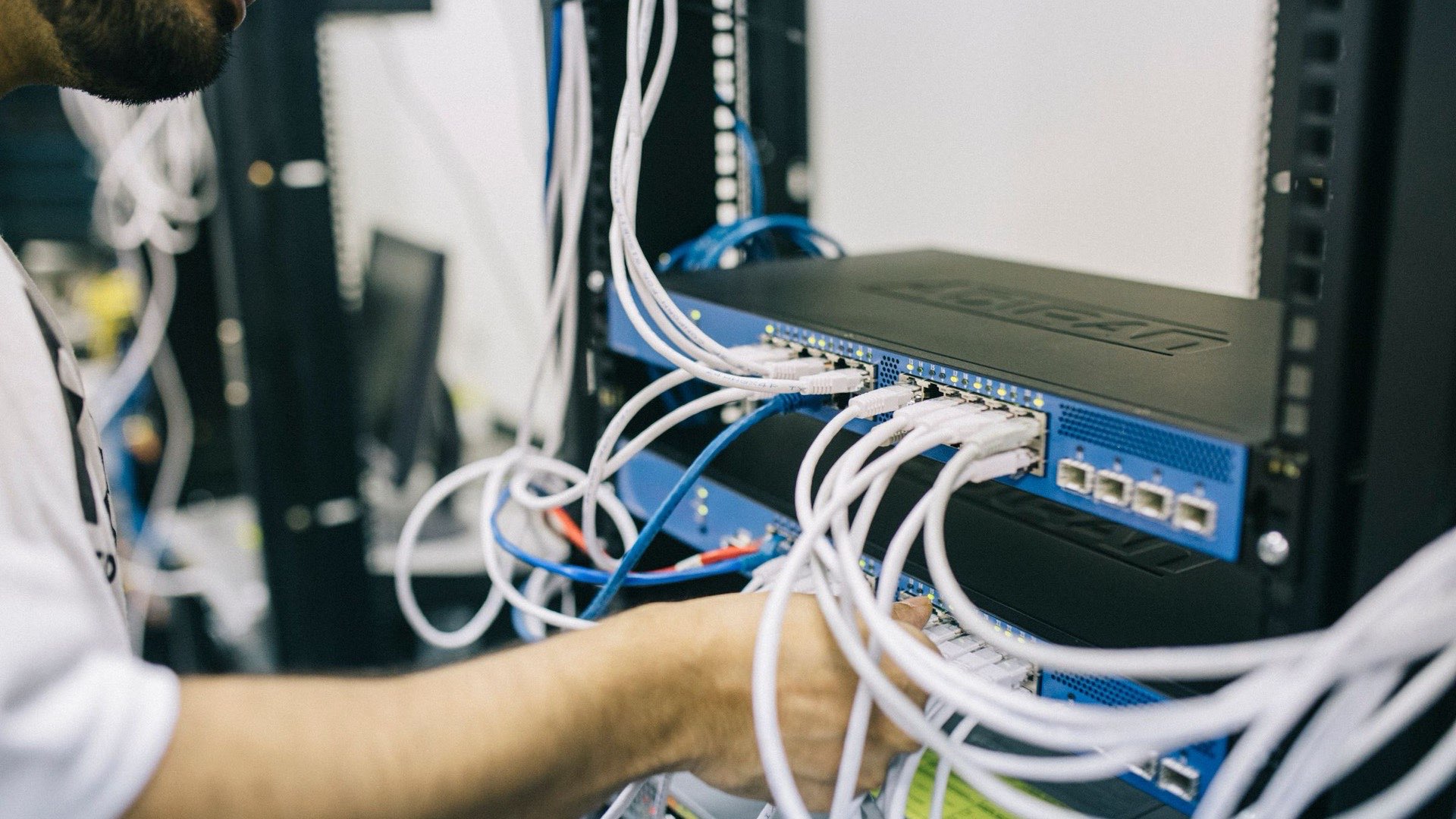 Técnico conectando cables de red en el rack de una empresa